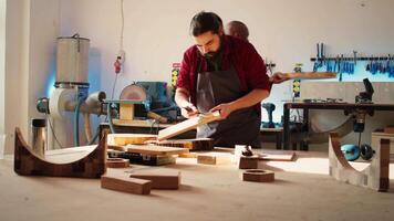 Carpenter in assembly shop starting renovation project on timber block, applying lacquer on surface. Woodworking specialist coloring wood plank with paintbrush, enjoying diy hobby, camera B video