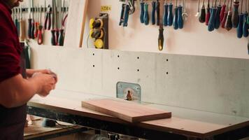 homme en mettant sur protection équipement tandis que insertion planche dans broche mouleur à prévenir lieu de travail les accidents. Charpentier équipement sécurité des lunettes tandis que Coupe bois avec bois façonneur, caméra une video