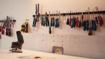 Chisels, screwdrivers, wrench and pliers on wall in carpentry studio, panning shot. Close up of various woodworking tools on rack in workshop used for repairing or creating wooden objects video