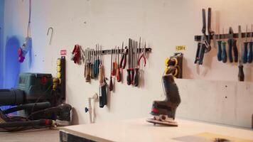 Electric router with woodworking tools on rack in background in workshop. Focus on hand powered equipment in front of chisels, screwdrivers, on wall in carpentry studio, panning shot video