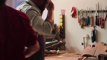 bipoc Zimmermann im Holzbearbeitung Geschäft inspizieren Holz Stück Vor Montage Möbel, Überprüfung zum Kratzer. Schreiner bewertet Bauholz Block, pflücken richtig Werkzeug von Gestell zum Es, Kamera ein video