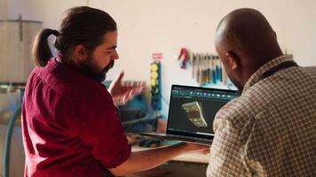 marceneiro olhando sobre plantas em computador portátil dentro cafajeste Programas com Aprendiz. fabricante e colega de trabalho concepção personalizadas 3d mobília em caderno dentro estúdio, preparando para cliente ordem, Câmera uma video