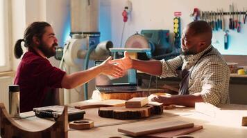 Schreiner zittern Kollege Hand nach Fertigstellung mit cad Software auf Laptop zu Design hölzern Objekte. Tischler Glückwunsch jeder andere zum Job Gut erledigt im Möbel Montage Geschäft, Kamera ein video