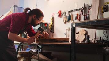 Mann Carving kompliziert Designs in Holz mit Meißel und Hammer im Zimmerei Geschäft, genießen DIY Hobby. Holzbearbeitung Spezialist im Studio Gestaltung hölzern Stücke mit Werkzeug, Herstellung Holz Kunst, Kamera b video