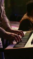 Vertical Musician playing piano midi controller in control room at professional recording studio, creating sounds with electronic keyboard notes. Sound engineer does mix and master on files. Camera B. video