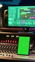 Vertical Professional audio expert mixing and mastering tracks in music production studio, pushing buttons and switchers in control room. Sound engineer recording tunes with greenscreen tablet. Camera B. video