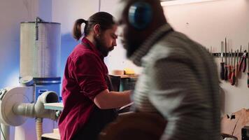 Carpenter drawing blueprints on notepad in studio, transforming creative ideas into tangible wood art pieces. Artisan looking at technical schematics to execute woodworking projects, camera A video