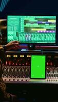 Vertical Team of producer and artist use tablet with mockup display in professional studio, mixing and mastering tracks after recording session. Experts working in control room with console. Camera B. video