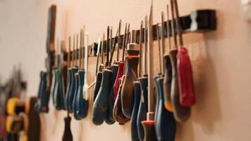 Chisels, screwdrivers, wrench and pliers on wall in furniture assembly shop, panning shot. Close up of various woodworking tools on rack in joinery used for working with wood materials video