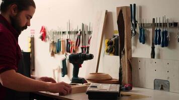 Zimmermann Ändern Leistung bohren Kopf in geeignet einer zum Aufgabe voraus, Herstellung Löcher in Bauholz Block. Schreiner im Versammlung Geschäft vorbereiten elektrisch Ausrüstung Werkzeug zu verwenden zum in Auftrag Arbeit, Kamera ein video