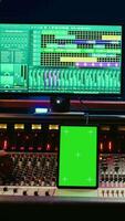 vertical diverso música expertos trabajando con pantalla verde en tableta y mezcla consola en controlar habitación, prensado llave botones y emprendedor deslizadores artista y productor creando un golpear canción en estudio. cámara b. video