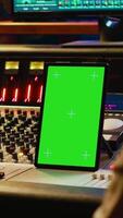 Vertical Diverse music experts working with greenscreen on tablet and mixing console in control room, pressing key buttons and pushing sliders. Artist and producer creating a hit song in studio. Camera A. video