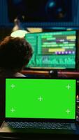 Vertical Artist and sound designer working as a team to produce new tracks, greenscreen laptop. Musician and audio technician collaborating on music, mixing on audio console with motorized faders. Camera B. video