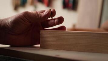 Woodworker using power drill to create holes for dowels in wooden board, close up. Carpenter sinks screws into wooden surfaces with electric tool, doing precise drilling for seamless joinery, camera A video