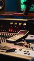 Vertical Control room with technical equipment and music recording software, professional studio editing and producing tracks. Audio console with moving faders and colored meters, high quality sounds. video