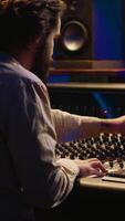 Vertical Mixing engineer focuses on blending and balancing individual tunes of a recording to create song, audio editing software in control room. Expert deals with technical aspects of sound. Camera A. video