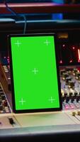 Vertical Professional audio expert mixing and mastering tracks in music production studio, pushing buttons and switchers in control room. Sound engineer recording tunes with greenscreen tablet. Camera A. video