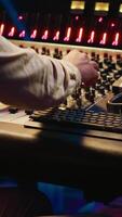 Vertical Mixing engineer pressing sliders on control desk to balance tracks and add sound effects, creating new music. Audio engineering expert works with motorized faders in professional studio. Camera A. video