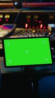 Vertical African american tracking engineer works with greenscreen, operates audio console with moving faders and colored meters. Specialist pressing buttons and faders to edit audio recordings. Camera A. video