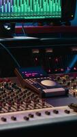 Vertical Professional studio control room with pre amp knobs and faders, key buttons on recording desk, soundproof space. Audio mixer and regulator used to produce music, technical equipment. video