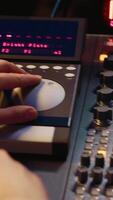 verticaal geluid ontwerper werken met schuifregelaars en overstappers Aan controle bureau in professioneel muziek- opname studio, bewerken en produceren liedjes voor een nieuw album. technicus aanpassen volume niveaus. camera a. video