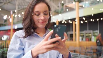 een vrouw in bril is op zoek Bij haar telefoon video