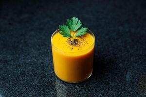 Mango Carrot Apple Smoothie in a glass on dark background with glass straw photo