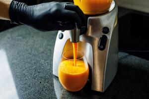 Mango Carrot Apple Smoothie getting poured into a glass from a smoothie maker photo