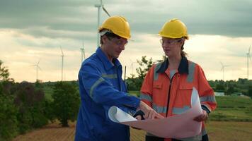 Smart engineer with protective helmet holding the blueprint working at electrical turbines field video