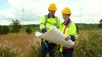 Smart engineer with protective helmet holding the blueprint working at electrical turbines field video