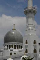 White mosque with beautiful domes and clouds photo