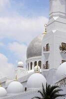 White mosque with beautiful domes and clouds photo