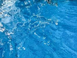 Background dynamic splash of clear water creating swirling wave in blue water with droplets suspended in motion. Clean water concept. photo