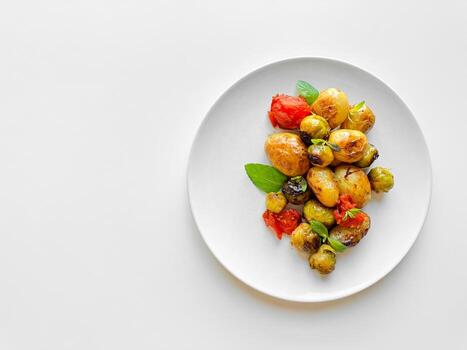 gastos generales ver de plato con asado bebé papas, Bruselas coles, y Cereza Tomates adornado con Fresco albahaca, limpiar comiendo concepto con Copiar espacio. foto