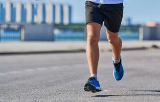 Athletic man jogging in sportswear on city road photo