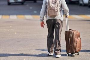 Old man with suitcase on wheels photo