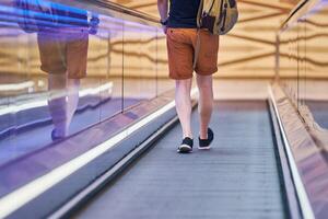 Young man goes down on moving walkway in shopping center photo