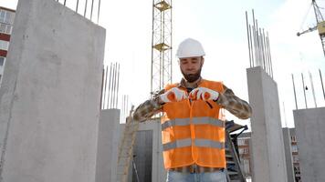 Baumeister Handwerker, Vorarbeiter im schützend Helm und Weste steht beim Arbeitsplatz im Gebäude und hält Lineal im Hände video