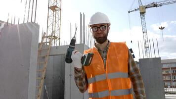 reparador trabajador en uniforme y casco participación sin cable destornillador, en pie en su lugar de trabajo video