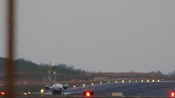 privato Jet aereo è assunzione spento, posteriore Visualizza attraverso il recinzione. pista di decollo illuminazione con atterraggio luci video