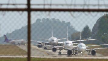 Airplanes row on the airfield, view through the airport fence, haze. Aircraft standing on airfield. Traffic At Busy Airport video