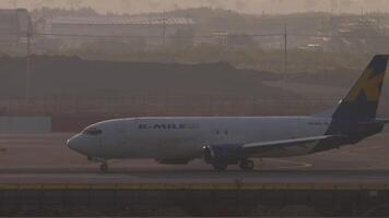 BANGKOK, THAILAND - MARCH 02, 2023. Side view of Boeing 737, HS-KMA of K-Mile Air on the runway at Suvarnabhumi airport, sunset time. Express airline, cargo plane video
