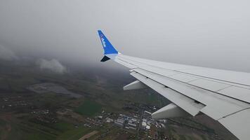 Krakau Polen 1.04.2024 Flugzeug Flügel hochfliegend Über ländlich Landschaft, Aussicht von Flugzeug Fenster von das Flügel hochfliegend Über ein ländlich Landschaft mit Felder, klein Städte, und bedeckt Himmel. video