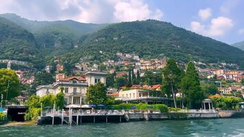 Colorful Waterfront Town on Lake Como, Vibrant and picturesque waterfront view at Lake Como with elegant buildings and lush trees against a backdrop of rolling hills. video