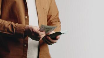 Young man in casual clothes standing and counting fast the stack of banknotes on a white background in the studio close up. Concept of careful financial accounting video