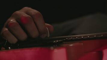 Close-up view of hands of a guitar player performing on an electric guitar with a pick under the concert light on a stage, bottom view. Musician playing fast song during the show video