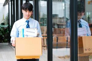 Man leaves office holding a box with personal items, including resignation letter. photo