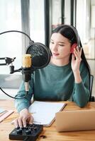 A woman is sitting at a desk with a microphone and a laptop photo