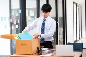 A man in a suit is opening a cardboard box on a desk photo