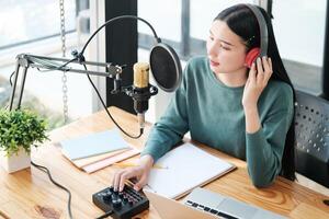 A woman is sitting at a desk with a microphone and a laptop photo